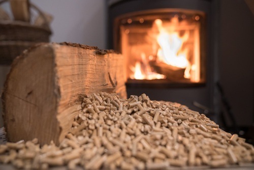 Tas de granulés de bois devant une bûche et un poêle allumé